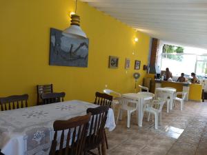 佩鲁伊比Guaraú Praia Suítes的餐厅设有白色的桌椅和黄色的墙壁