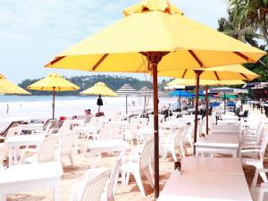 米瑞莎Fresh Wave Mirissa - Beach Front的海滩上设有白色椅子和黄色遮阳伞