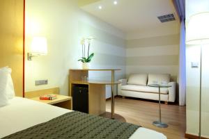 阿利坎特Eurostars Centrum Alicante的酒店客房配有一张床、一张书桌和一张沙发。