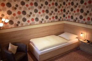 巴特德里堡厄歇尔酒店的一间小卧室,配有一张床和一把椅子