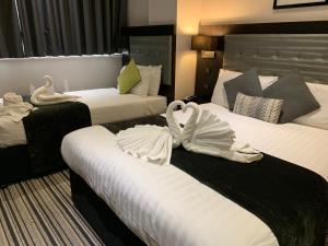 伦敦The W14 Kensington的两张床铺,位于酒店客房内,配有天鹅