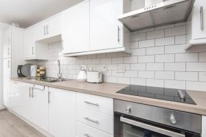 阿马The Gem的厨房配有白色橱柜和炉灶烤箱。