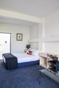 帕拉帕拉乌姆海滩U Studios Paraparaumu Beach的一间卧室配有一张床、一张桌子和一把椅子