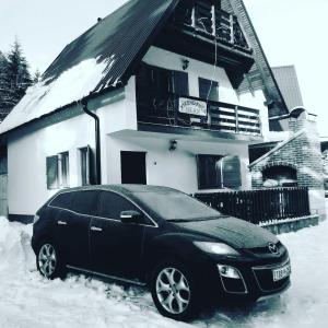 弗拉西克Vikend Kuća Iman的一辆停在房子前面雪地里的黑色汽车