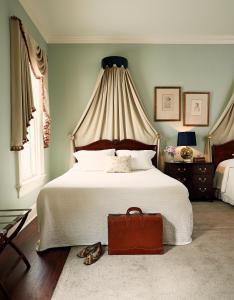 查尔斯顿约翰拉特利奇楼酒店的一间卧室配有一张大床和棕色的行李箱