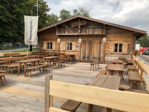 慕尼黑慕尼黑啤酒节维森营地旅馆的木质建筑,配有木桌和长椅