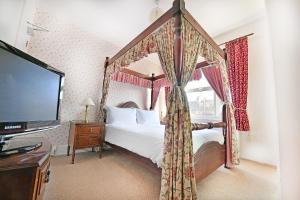 埃文河畔斯特拉特福弗吉尼亚旅馆的一间卧室配有天蓬床和一台平面电视