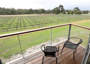 Upper SwanLot113 Vineyard Accommodation的两把椅子坐在一个甲板上,眺望着葡萄园