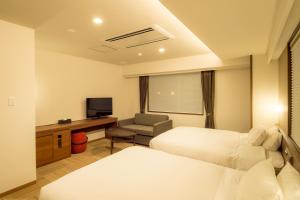 富良野Hotel Munin Furano的酒店客房设有两张床和电视。