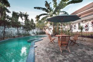 雅加达Capital O 332 Residence G17 Kemang的游泳池旁配有遮阳伞的桌椅