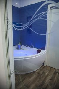 托雷阿马莱VILLA ADELAIDE SUITE & ROOM的浴室设有白色浴缸,拥有蓝色的墙壁
