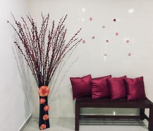 马六甲巴克卡迪因达旅舍的配有红色枕头的长凳和花瓶