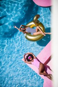 普拉亚登博萨Tropicana Ibiza Suites - Adults Only的两个女人躺在游泳池里的木筏上