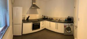 阿伯丁布卢姆菲尔德 - 阿伯丁服务式公寓的厨房配有白色橱柜、洗衣机和烘干机