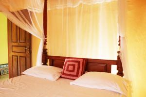 高尔Ariyadasa Guest House的一间卧室配有一张带两个枕头的天蓬床