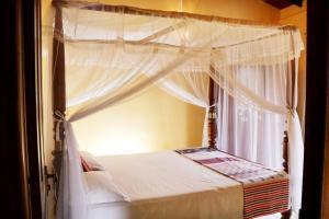 高尔Ariyadasa Guest House的一间卧室设有天蓬床和窗户。