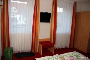 图特林根Donau Pension的一间卧室配有橙色窗帘、一张床和电视