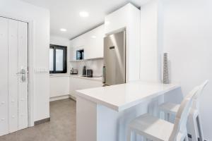 马贝拉by RIVA - Beautiful 1 Bedroom Chic Apartment in Banus Gardens的白色的厨房配有白色橱柜和冰箱。