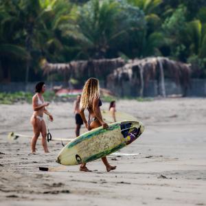 PetacaltepeTapas & Surf的一名妇女在海滩上拿着冲浪板