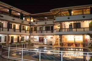 亨达El Virrey Hotel Boutique的一座大型建筑,晚上设有游泳池