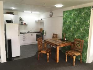 DinsdaleSmart Apartment的厨房配有木桌、椅子和冰箱。