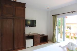 湄南海滩香格里拉哈简易别墅酒店的一间卧室设有大型木制橱柜和电视