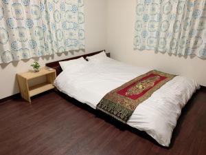 东京Tokyo Kamakura House的一间小卧室,配有一张带白色床单和一张桌子的床