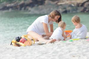沙美岛敖卓静谧度假酒店的一名妇女和两名儿童坐在海滩上