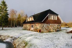 LimuLoovälja Guesthouse的河边雪地中的石头房子