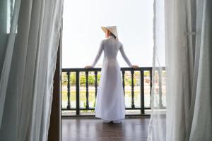 会安Little Hoi An . A Boutique Hotel & Spa的站在阳台上的穿着白色衣服的女人