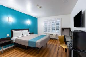 芳泉谷喷泉谷/亨廷顿海滩戴斯酒店&套房的一间卧室设有一张床和蓝色的墙壁
