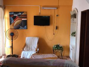 贝尔马尔Sun Tropical Paradise的一间带椅子和墙上电视的房间