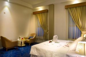 哈萨Fiori Hotel Suites的酒店客房,配有一张床和两把椅子
