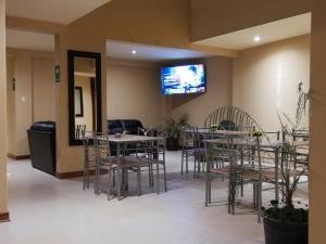 卡哈马卡Hotel Caxa Wasi的一间带桌椅的餐厅以及墙上的电视