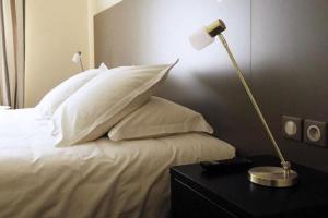 图尔龙萨酒店的一张带白色枕头的床和一张桌子上的台灯