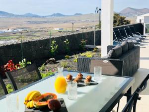 纳萨雷特Canaryislandshost l Infinity Views的美景阳台上的一张桌子,上面摆放着水果和果汁