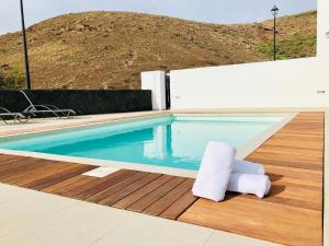 纳萨雷特Canaryislandshost l Infinity Views的一个带椅子的游泳池,位于木甲板上