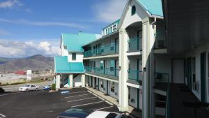 坎卢普斯高山汽车旅馆的一座设有蓝色阳台和停车场的建筑