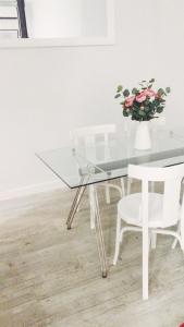 马德里Reina Victoria 46的玻璃桌,带白色椅子和花瓶
