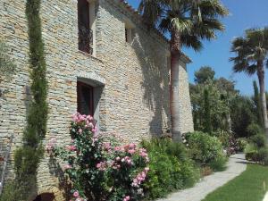 勒卡斯特雷特La Bastide de l'Oliveraie的一座砖砌的建筑,花朵和棕榈树