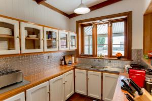 SpringtonGrand Cru Estate Homestead的厨房配有白色橱柜、水槽和窗户。