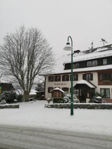 施卢赫湖Höhengasthof Rössle的雪中建筑物前面的街道灯