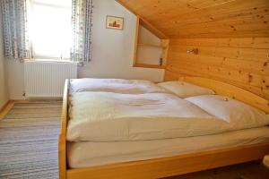 LeisachKlausmoarhof的木制客房内的一张大床,设有窗户