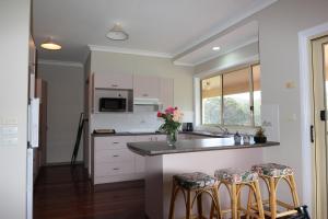 Mount GeorgeRural Ambience with Netflix的厨房配有白色橱柜和带凳子的台面