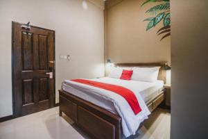 雅加达RedDoorz Plus near Mall Slipi Jaya的一间卧室配有一张带红色枕头的大床
