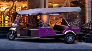 曼谷Amaranta Hotel - SHA Plus的停在大楼前的紫色高尔夫球车
