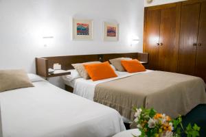伊瓜拉达Hotel America Igualada的配有橙色枕头的酒店客房内的两张床