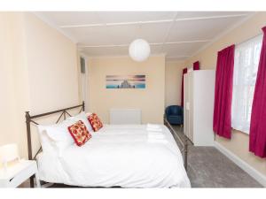 迪尔Sandown Villa Holiday Home的卧室配有白色的床和红色窗帘