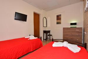 Mikro MetochiFarm Villas的一间卧室配有两张带红色床单的床和电视。
