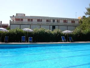 毕博纳的码头Appartamenti Marina del Forte的游泳池旁的三把椅子和遮阳伞